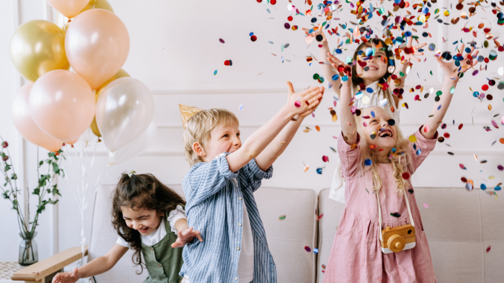 Imagen de un niño y tres niñas celebrando un cumpleaños tirando confeti