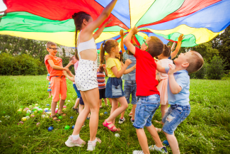 Niños jugando con un paracaídas de colores
